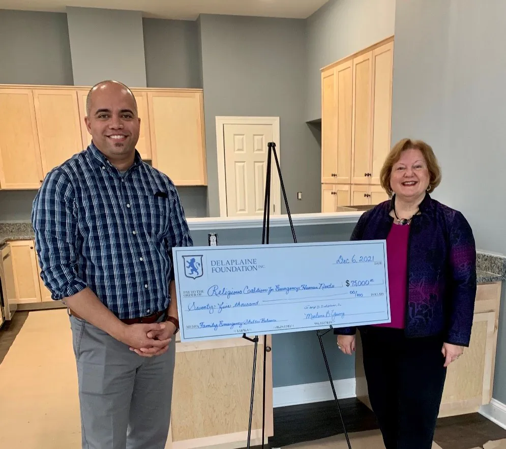 Religious Coalition Executive Director Nick Brown accepts grant check from Delaplaine Foundation President Marlene Young at Family Emergency Shelter